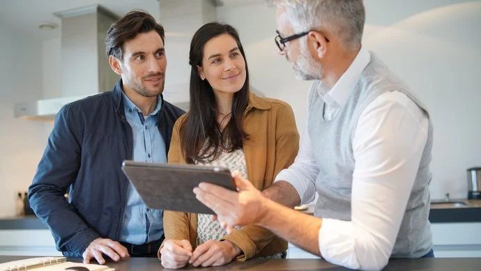 Ein Paar wird von einem Berater mit einem Tablet an einem Tisch beraten