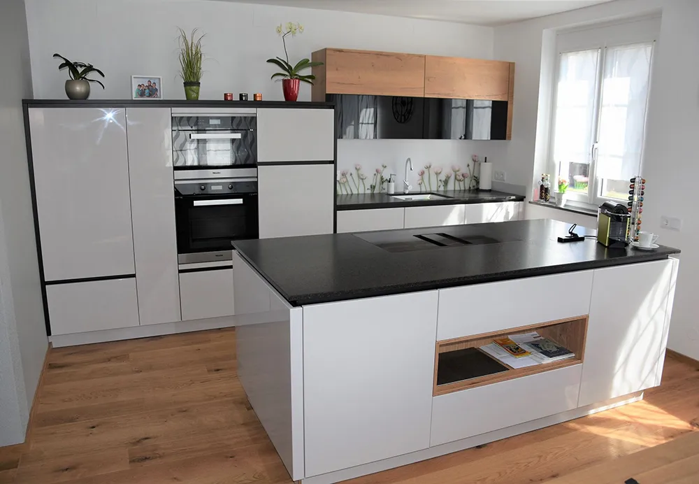 Moderne Küche mit mattweißer Verkleidung und Kochinsel mit schwarzen Arbeitsplatten und Akzenten mit oberen Holzschränken