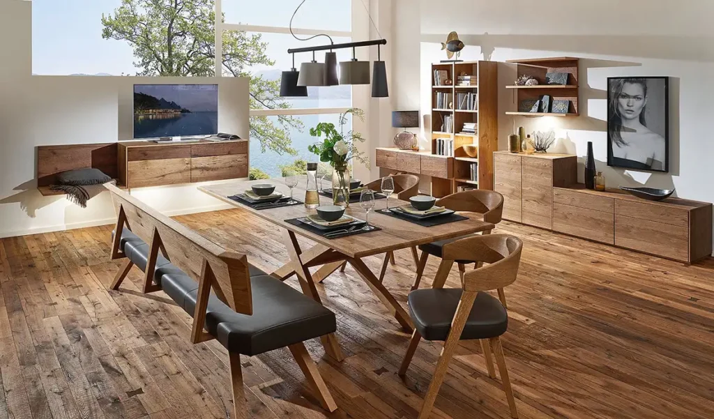 Wohnen - Esstisch aus Holz mit Kreuzbeinen gepolsterten braunen Lederstühlen und Bank mit niedrigen Regalen dahinter