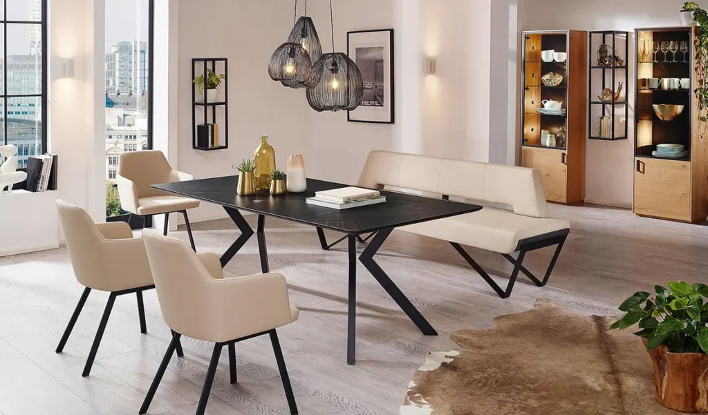 Wohnen - Esstisch aus dunklem Stein auf schwarzen Metallbeinen mit einer weißen Lederbank und drei Stühlen auf schwarzen Metallbeinen