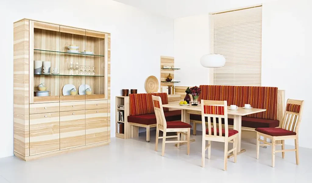 Wohnen - Holzbuffet mit Geschirr und Holztisch und -bank und Stühlen mit weicher roter Polsterung