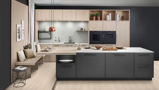 Große dunkle Kücheninsel vor einer Küchenzeile aus hellem Holz