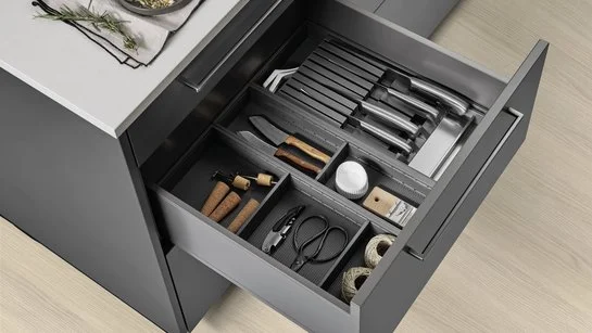 Messereinsatz und Utensilieneinsatz in einer geöffneten Schublade in einer Kücheninsel