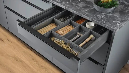 Messereinsatz und Utensilieneinsatz in einer geöffneten Schublade in einer Kücheninsel