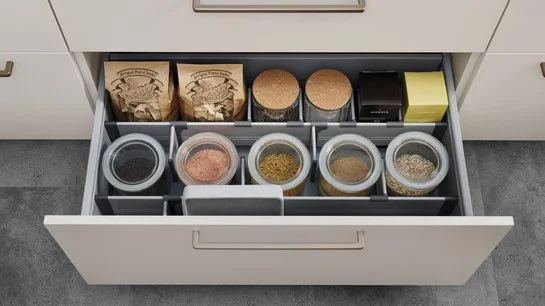 Offene Küchenschublade, darin ein mit Teilern eingeteiltes Ordnungssystem und Lebensmitteln
