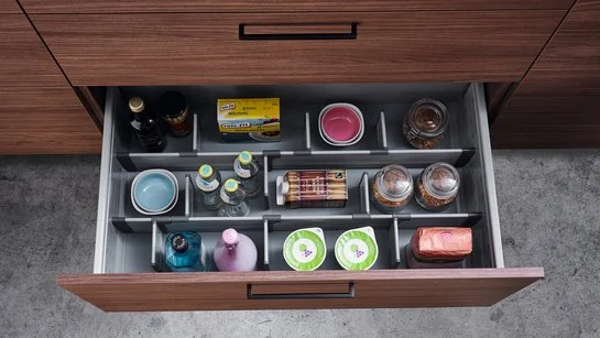 Offene Küchenschublade mit Einteilungssystem und Lebensmitteln darin