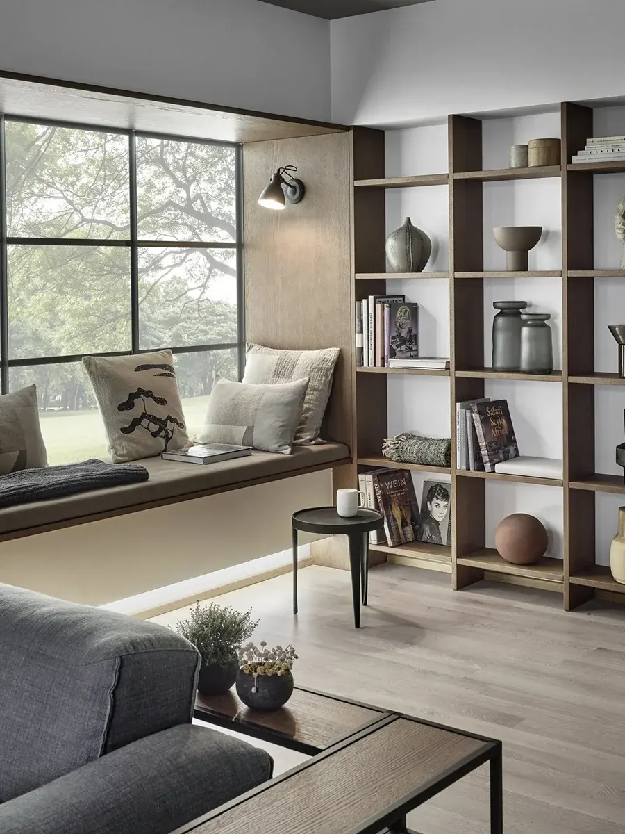 Eine gepolsterte Fensterbank und daneben ein offenes Holzregal