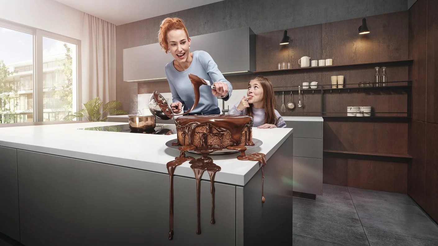Mutter und Tochter beim Schokotorte-verzieren in grauer Küche, alles tropft