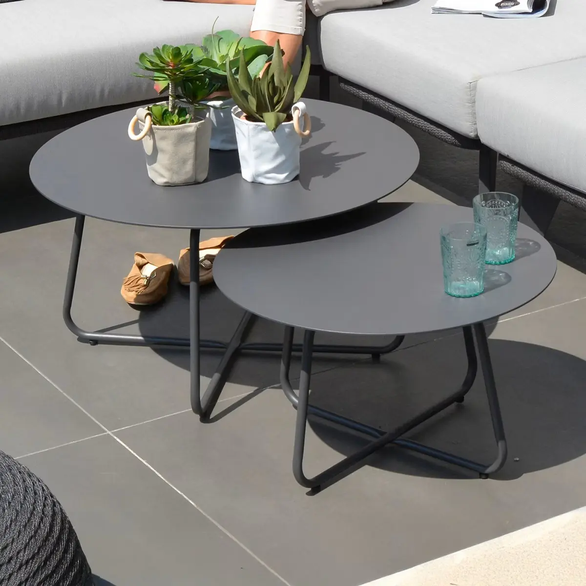 Zwei Tische mit Pflanzen stehen auf einer Terrasse.