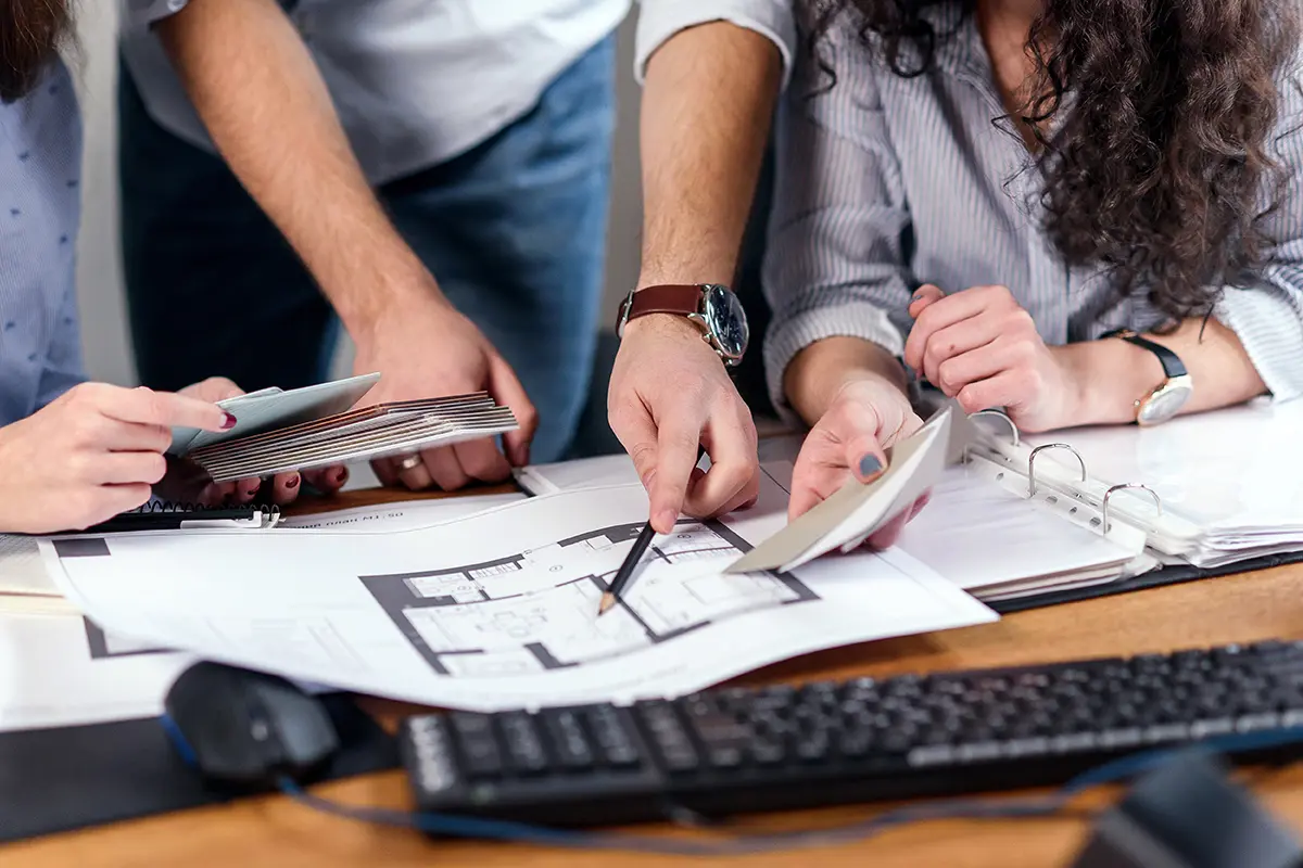 Drei Personen arbeiten gemeinsam am Tisch.
