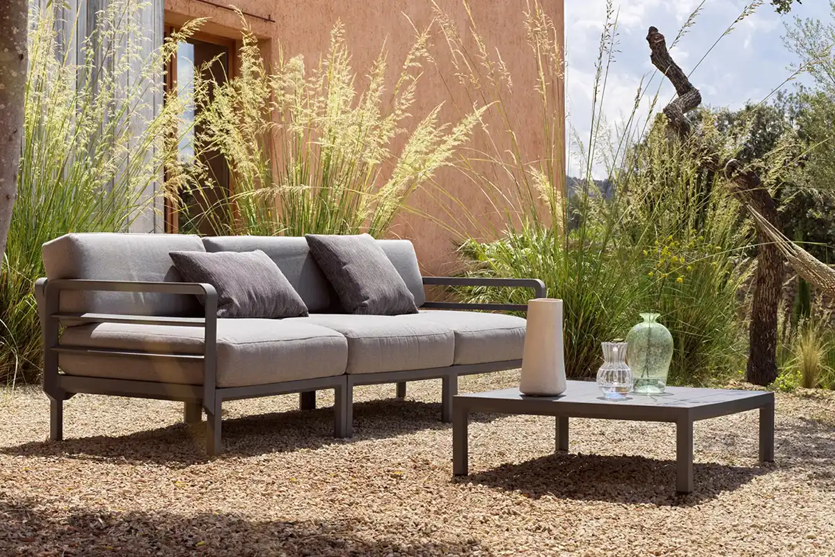 Weiche graue Outdoor-Couch und Couchtisch stehen vor Gebäude