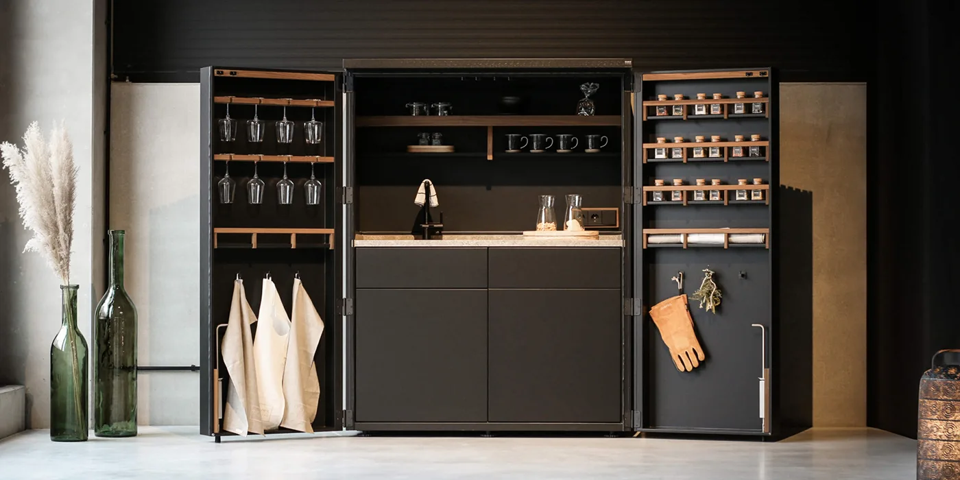 Mobile Outdoor-Küche mit vollständig verschließbaren Schränken und in die Türen integrierten Regalen.