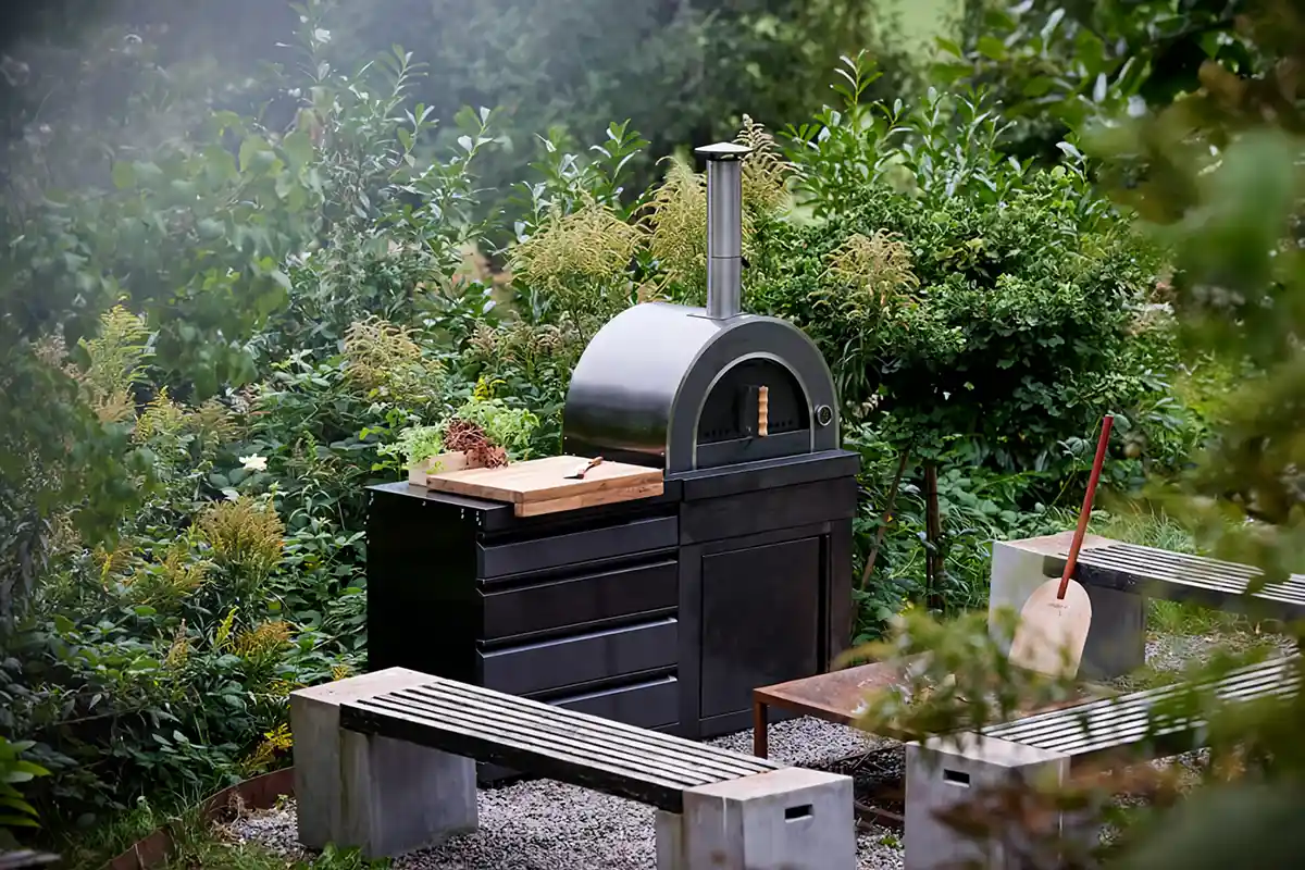 Eine schwarz-weiße Außenküche mit einer Bank, umgeben von Pflanzen und einem einladenden Ambiente